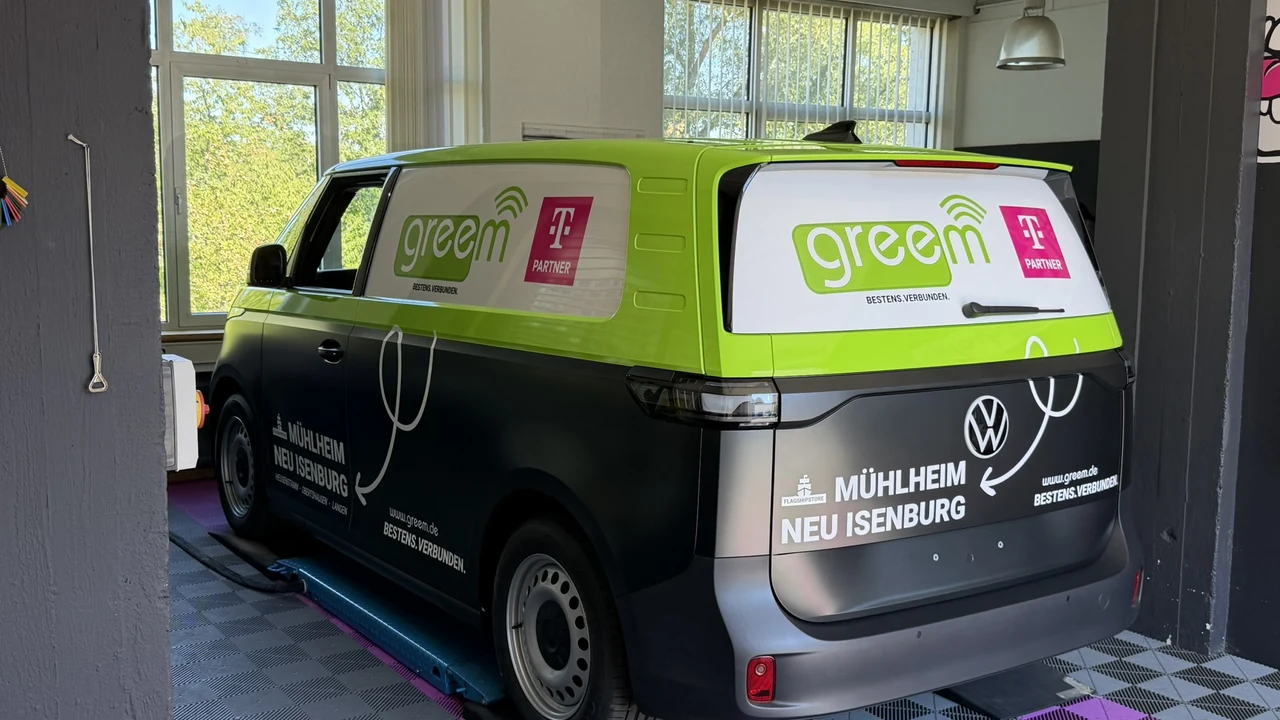 VW ID. Buzz Cargo in greem-Folierung von schräg hinten, mit greem-Logo und Telekom-Partner-Zeichen auf den Scheiben
