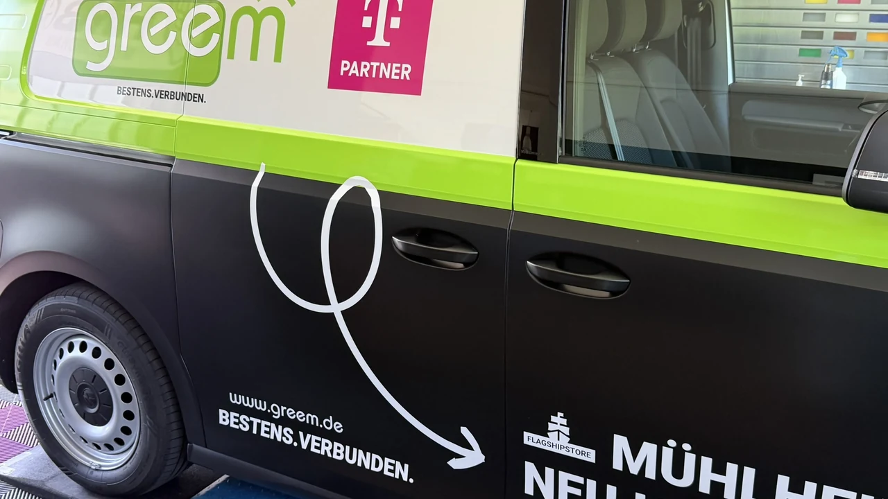 Nahaufnahme der Fahrzeugseite mit greem-Logo, Claim Bestens.Verbunden und dem Telekom-Partner-Zeichen